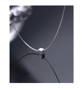 Macro shot of silver cube pendant with brushed metal texture on a delicate box chain