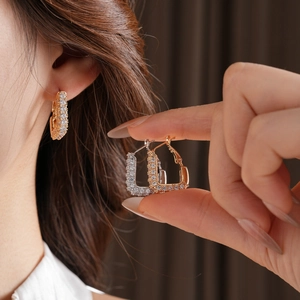 Détail des boucles d'oreilles pavées de zircone en forme de U en or et argent sur modèle