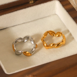 Detail of leaf-shaped gold and silver rings presented in a wooden jewelry box