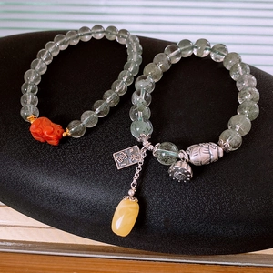 Macro shot of S925 silver lotus and amber pendant on green phantom quartz bead bracelet
