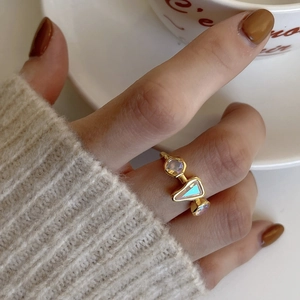 Detail of a gold geometric S925 silver ring with iridescent zircon on a woman's hand