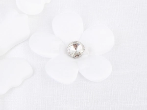 Macro shot of white fabric flower with a sparkling crystal center detail