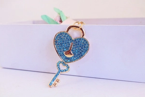 Detailed close-up of golden heart lock and key keychain with blue rhinestones