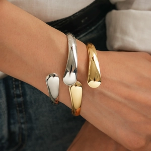 Minimalist metallic geometric open bracelet in gold and silver finish on wrist