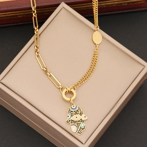 Macro shot of gold Hamsa hand pendant with colorful enamel eye on layered chain