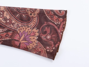 Détail de la manche en maille à motif paisley rouge avec texture semi-transparente