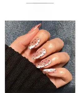 Close-up of almond-shaped cat-eye press-on nails with black polka dot design
