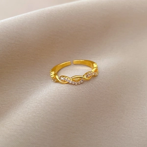 Makrofoto eines verstellbaren Goldrings mit Zirkonia-Mikropavé auf weichem Stoff
