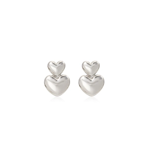 Close-up of polished silver heart-shaped stud earrings with double layered geometric design