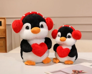 Detailed view of two plush penguins with red earmuffs and heart in two sizes