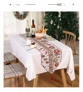 Detailed Christmas table runner with reindeer print and festive red tassels on dining table