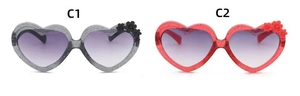 Detail view of heart-shaped kids sunglasses with glitter frames and 3D flower accents