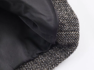 Detailed close-up of brown herringbone tweed fabric and smooth black twill inner lining