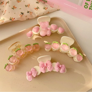 Detail of four cute pink peach and bear hair claws on a decorative tray for women