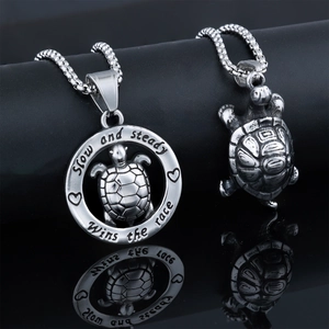 Close-up of stainless steel turtle pendants with engraving Slow and steady wins the race
