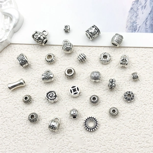 Detailed macro view of assorted vintage Tibetan silver spacer beads and hollow floral charms