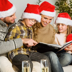 Family wearing plush red Christmas hats sharing a warm holiday book reading moment