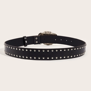 Punk style black leather belt with double silver studs and carved metal buckle on beige background
