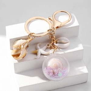 Detail van creatieve oceaan-sleutelhanger met schelp, zeester en hangers van paillettenbol