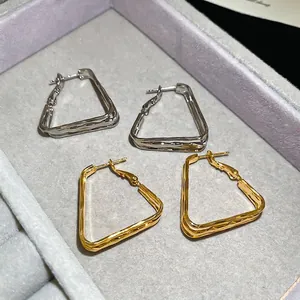 18k gold and silver plated geometric triangular hoop earrings on grey velvet display