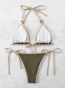 Detailed flat lay of two-tone bikini with amber ring accents on marble background