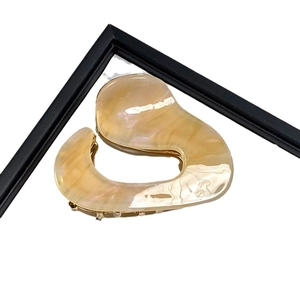 Irregular acetate shark hair claw clip in pearlescent beige with golden metal accents