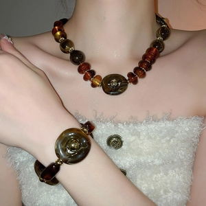 Detail view of acrylic tortoiseshell necklace and bracelet set on a female model