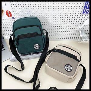 Detail of minimalist green and beige square crossbody bags with mesh pocket and strap
