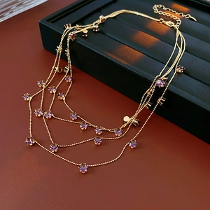 Détail d'un collier doré multicouche avec pierres rondes violettes et fermoir réglable