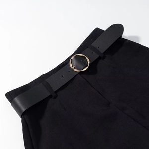 Close-up of black shorts with leather belt and golden round buckle detail