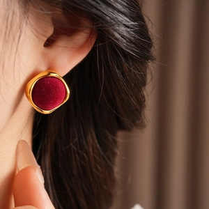 Gros plan de boucles d'oreilles carrées dorées avec velours rouge portées par un mannequin