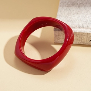 Macro detail of glossy red resin bangle showing the smooth wide square circular contour