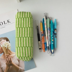Detail of green and white striped knit cosmetic pouch with stationery and magazine