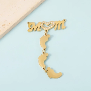 Detailed view of MOM letter pendant with heart stone and baby feet charms on stone