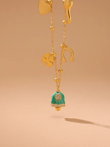 Detailed shot of 18K gold plated necklace with green enamel bell and heart charms