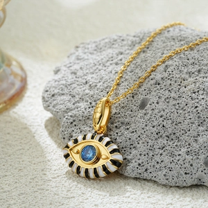 Macro shot of 18K gold evil eye pendant necklace with colorful enamel and blue zircon