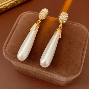 Detail of elegant teardrop pearl earrings with gold plating and sparkling crystals
