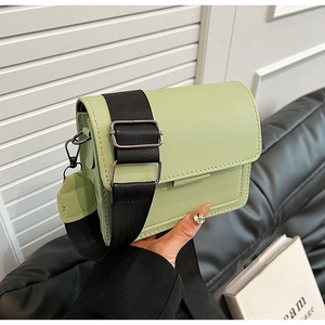 Detail of light green rectangular crossbody bag with adjustable wide black textile strap