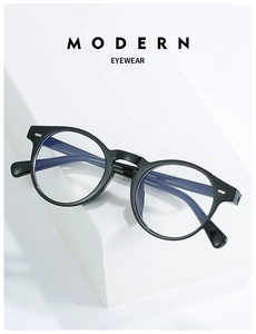 Detail view of round black frame glasses with silver rivets on a white display stand