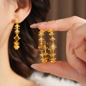 Macro shot of vintage gold earrings with tiger eye stone, pearls and pavé zircons