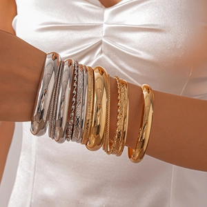 Close-up of a diverse metal bangle set featuring gold and silver mixed textured finishes
