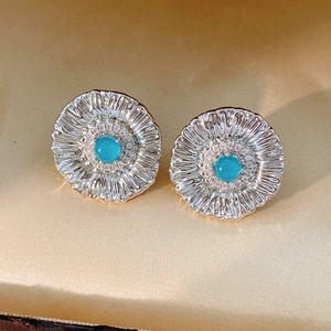 Macro shot of vintage silver sunflower earrings with blue stone on champagne silk