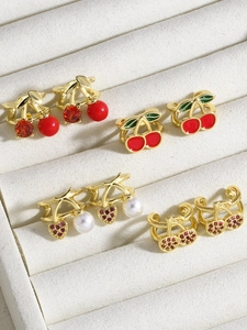 Detail of four cherry ear clips with red zircons and pearls on a velvet tray
