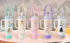 Detail of five colorful tumblers with woven straps and flower charms in a bright setting
