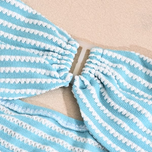 Detail of blue and white striped knit fabric featuring a central cream-white plastic buckle