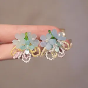 Macro detail of handmade colorful resin flower earrings with tiny seed beads and pearls