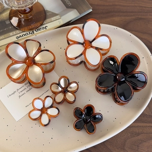 Detailed view of vintage amber flower hair claws in white and champagne on ceramic tray