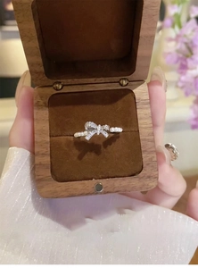 Close-up of bowknot zircon and pearl ring in a brown wooden jewelry case