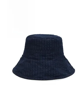 Détail d'un bob bleu marine avec broderie blanche 'one' et tissu à texture quadrillée