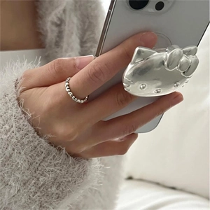 Detailed view of silver Hello Kitty 3D phone grip and wavy minimalist silver ring